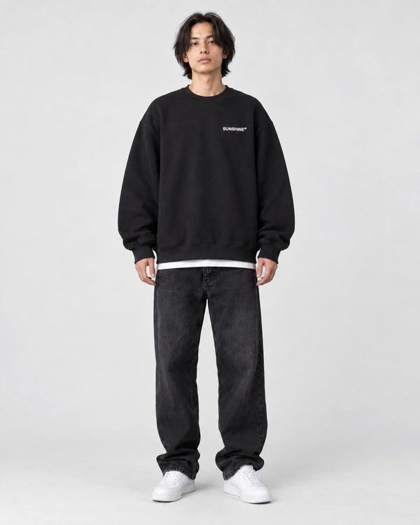 Model wearing the black sweatshirt with a small white chest print, front view