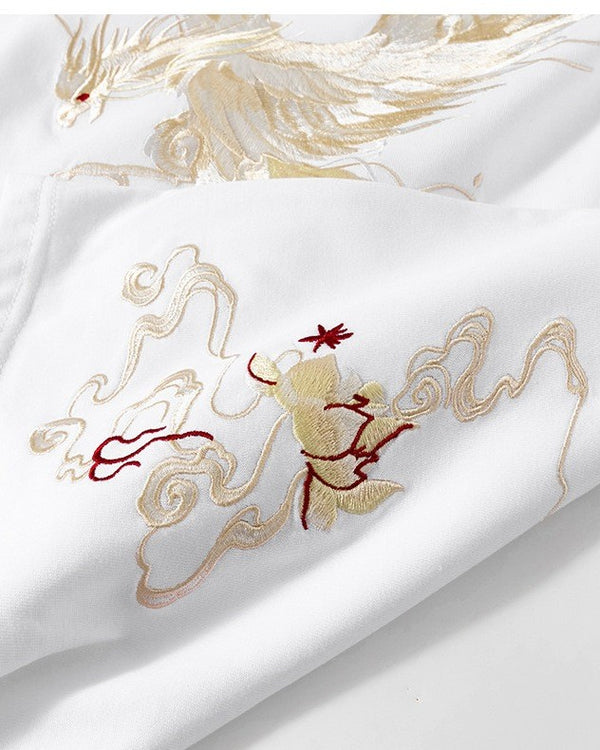 Close-up of the cream and gold phoenix embroidery on the white T-shirt
