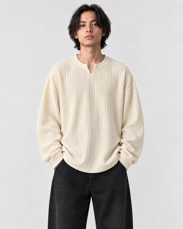 Model wearing the cream textured V-neck long sleeve tee with black trousers, front view