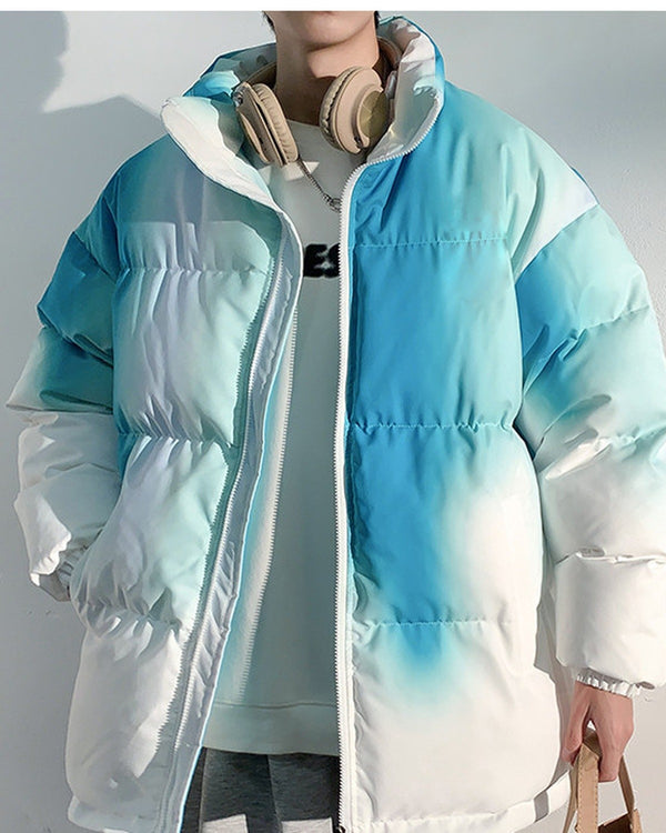Blue-green tie-dye puffer jacket worn open over a gray knit, torso view