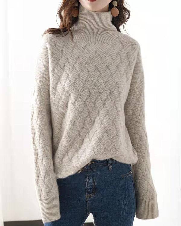 Front view of the beige woven-knit sweater with a ribbed folded mock neck, worn over blue jeans