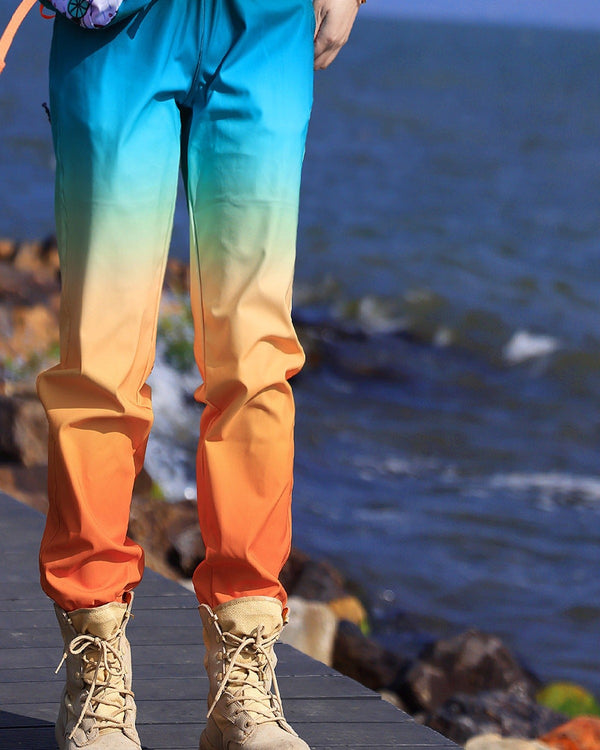 Gradient jogger pants fading from turquoise at the hips to cream at the knees and orange at the ankle cuffs, worn standing