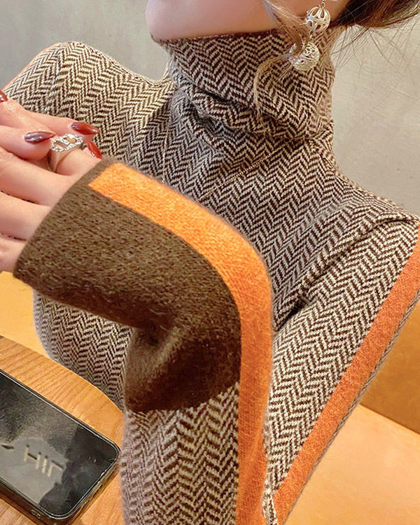 Close view of the orange sleeve stripe and brown wrist block on the herringbone turtleneck