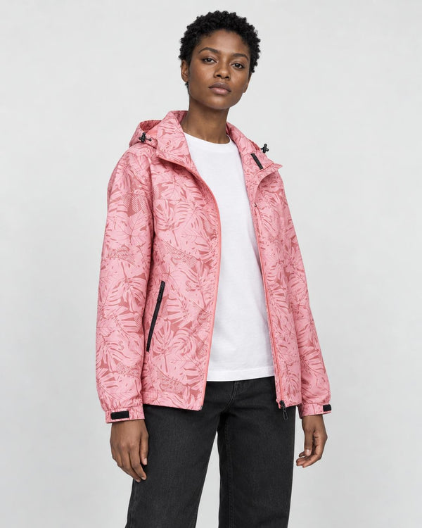Model wearing the pink leaf-print hooded windbreaker open over a white tee and black jeans, three-quarter view