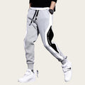Gray jogger pants with white and black side panels worn by a person on a gray background