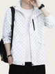 Person wearing a white jacket with black patterns on a plain background