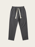 Dark gray jogger pants with white drawstring on a light beige background