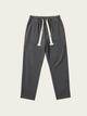 Dark gray jogger pants with white drawstring on a light beige background