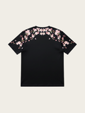 Black t-shirt with pink floral designs on a beige background