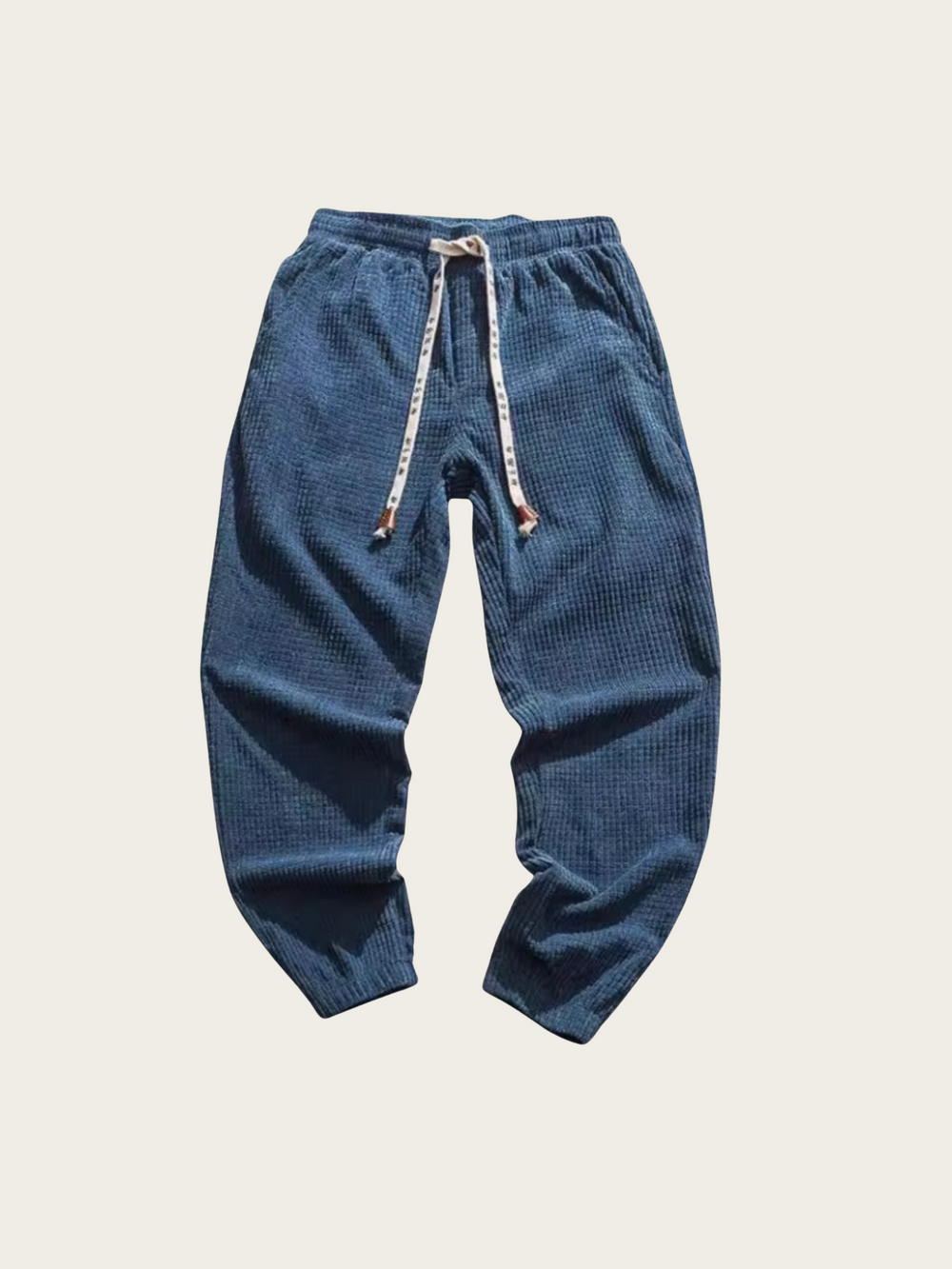 Blue corduroy pants with drawstring on a light beige background
