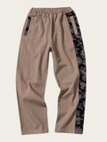 Beige pants with black floral side panels on a beige background
