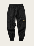 Black cargo pants with multiple pockets on a beige background