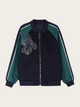 Black and green jacket with a design on the chest against a beige background
