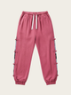 Pink jogger pants with side stripes on a beige background