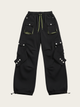Black cargo pants with multiple pockets and buttons on a beige background