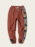 Brown jogger pants with floral pattern on the side on a beige background
