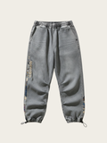Gray jogger pants with brand logo on a light beige background