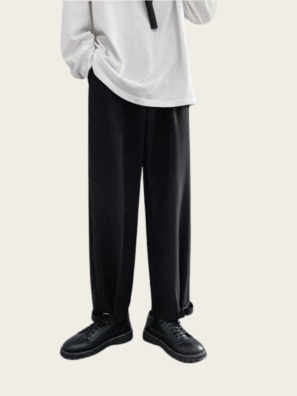 Person wearing a white shirt and black pants on a plain background