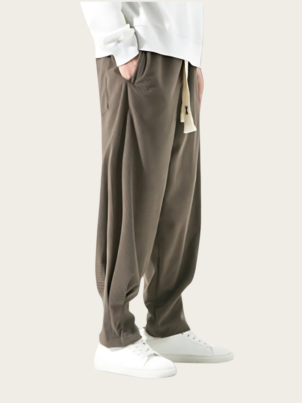 Person wearing brown pants and white shoes on a plain background