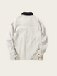 White jacket with black collar on a light beige background