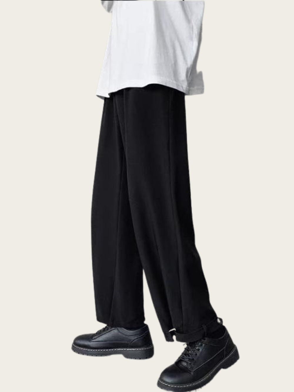Person wearing black wide-leg pants with a white shirt on a light beige background