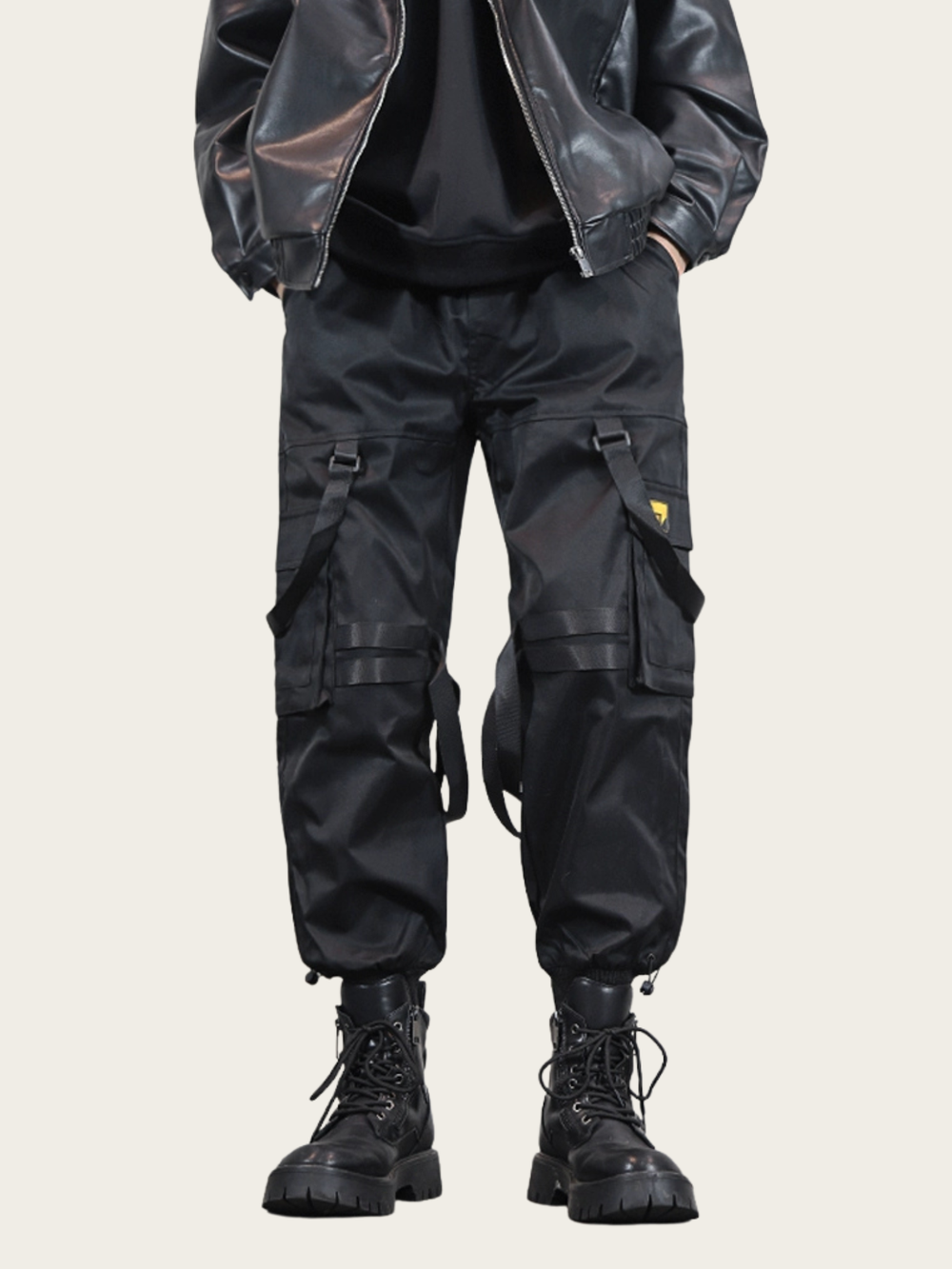 Person wearing black cargo pants and boots on a beige background
