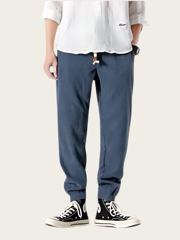Person wearing blue pants and black sneakers on a white background
