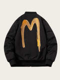 Black jacket with gold abstract design on the back against a beige background