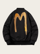 Black jacket with gold abstract design on the back against a beige background