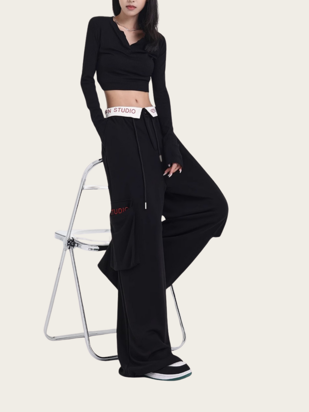 Person wearing a black outfit with 'STUDIO' waistband on a white background