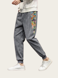 Gray jogger pants with colorful side patch worn by a person on a white background