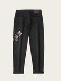 Black jeans with floral embroidery on a beige background