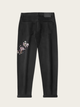 Black jeans with floral embroidery on a beige background