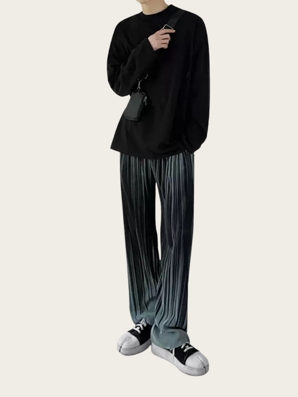 Person wearing a black sweater and pleated pants on a white background