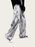 Person wearing gray tie-dye pants on a plain background