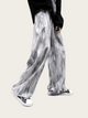Person wearing gray tie-dye pants on a plain background