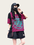 Person wearing a black and red striped shirt with text, black skirt, and cap on a plain background