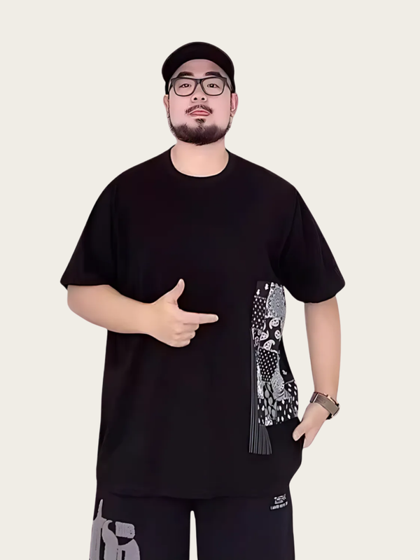 Man wearing a black t-shirt with a graphic design on a plain background