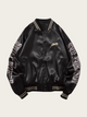 Black satin bomber jacket with text on sleeves against a beige background