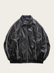 Black leather jacket with white stitching on a beige background