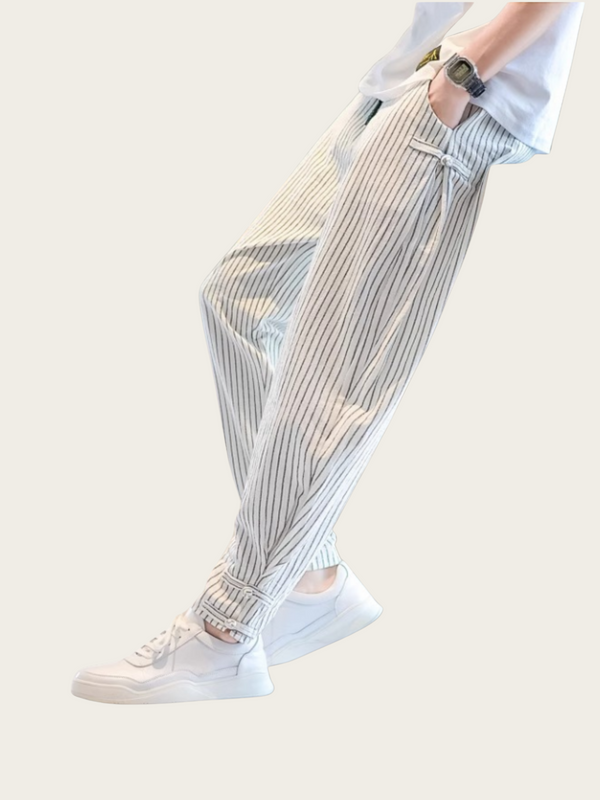 Person wearing light-colored striped pants and white sneakers on a plain background