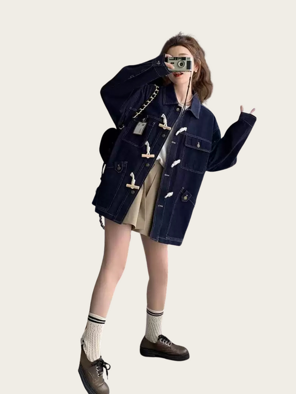 Person wearing a dark blue denim jacket on a plain background