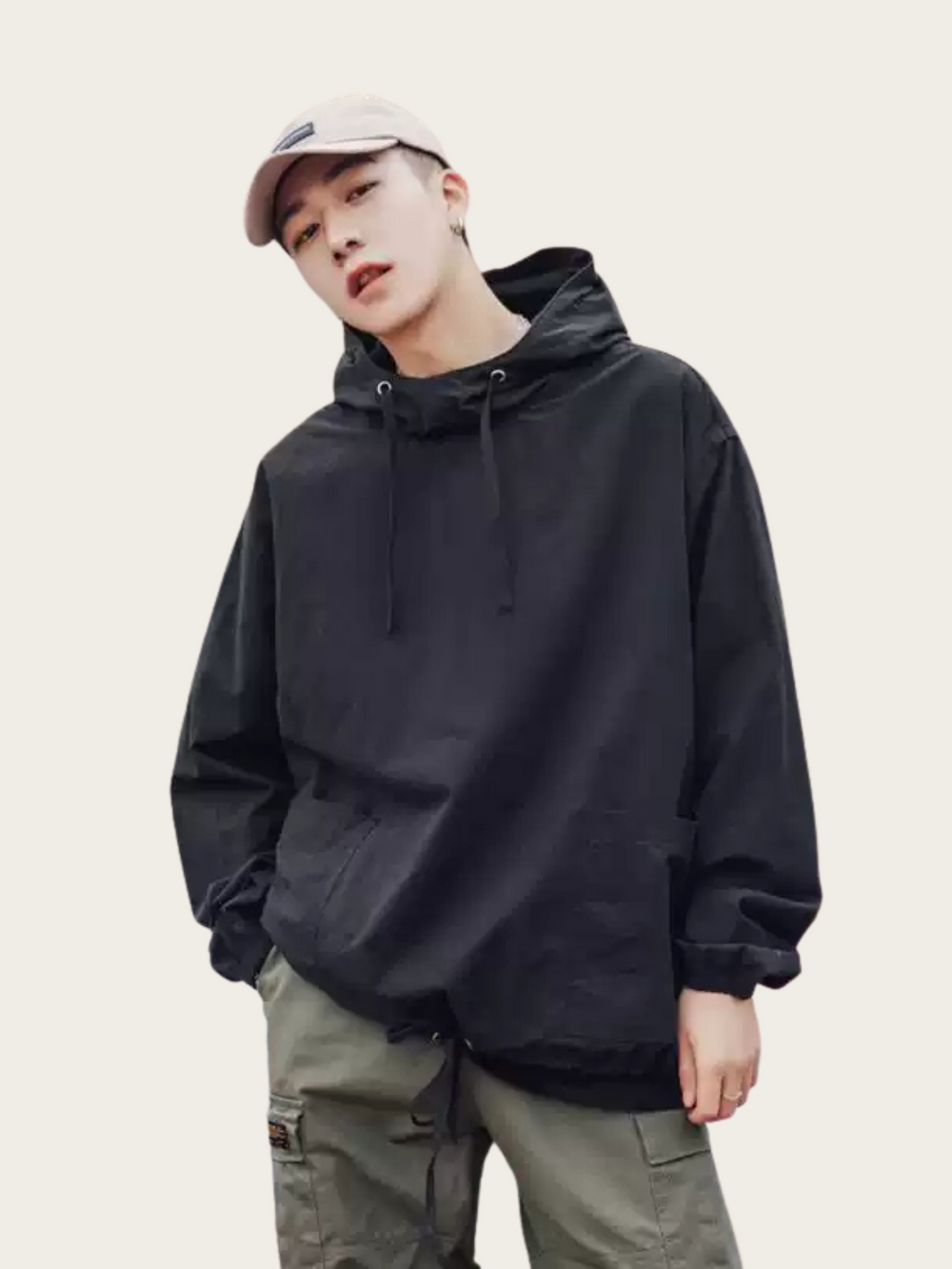 Person wearing a black hoodie and light-colored pants on a plain background