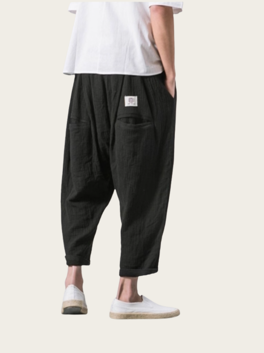 Person wearing black baggy pants and white shoes on a white background