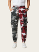 Camouflage jogger pants with red accents worn by a person on a white background