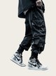 Person wearing black cargo pants and silver Nike sneakers on a light beige background