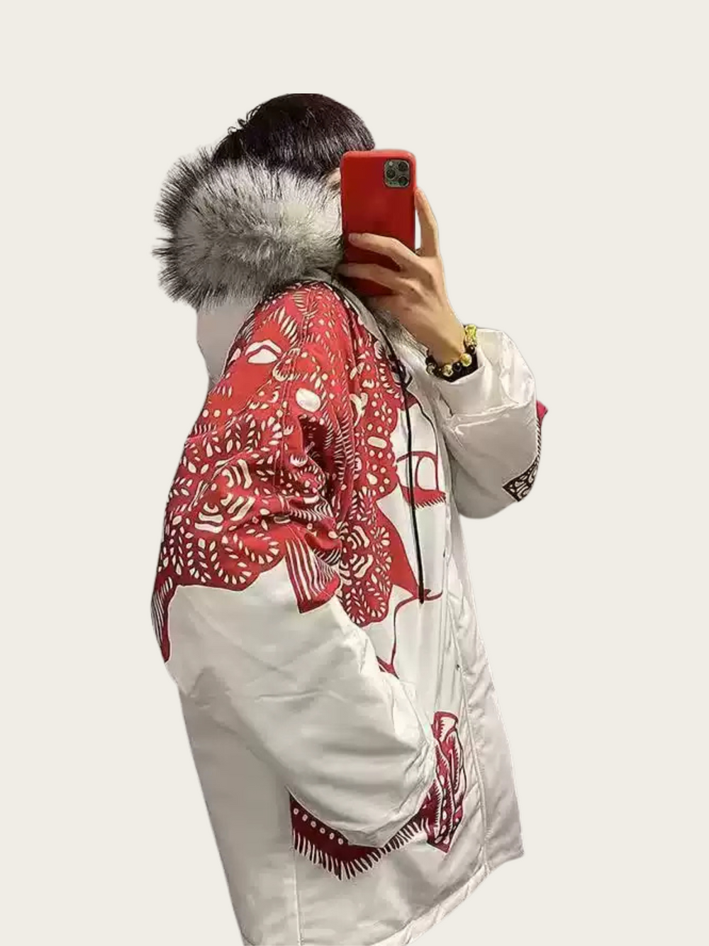 Person wearing a white and red patterned jacket with fur hood on a plain background
