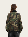 Person wearing a camouflage jacket on a plain background