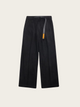 Black pants with a small orange tag on a beige background