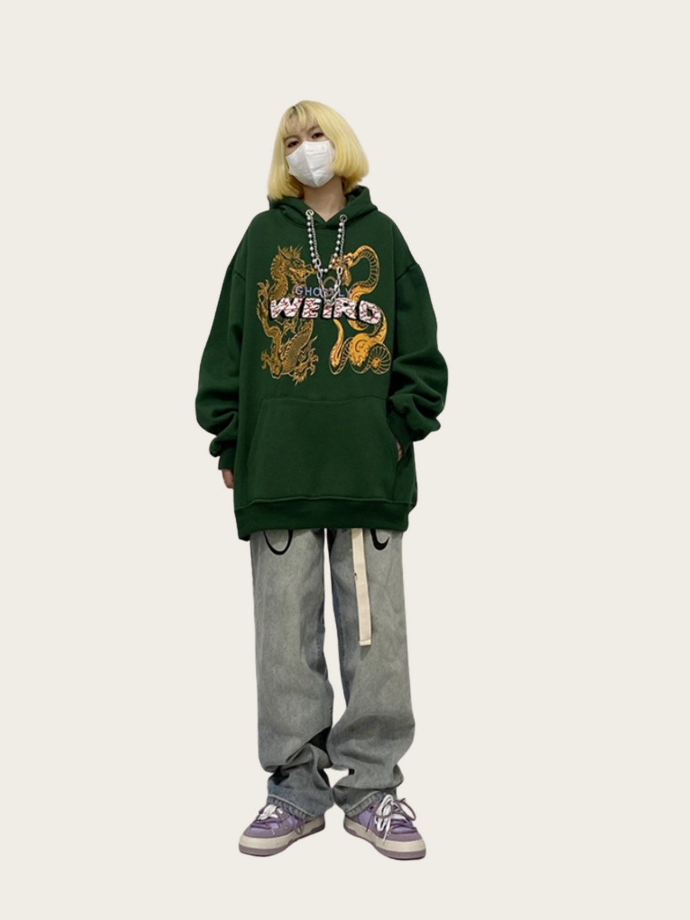 Person wearing a green hoodie with a graphic design and text, standing against a plain background